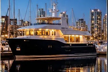 Slide: The Image of Luxurious 2026 Monarch 75 Dauntless yacht docked at night with city skyline backdrop. - 2