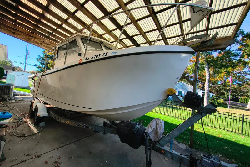 Slide: The Image of 2004 Osprey 26 Fisherman boat on trailer under a covered area. - 18