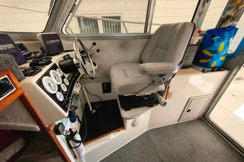 Slide: The Image of 2004 Osprey 26 Fisherman boat cockpit with steering wheel, gauges, and captain's chair. - 14
