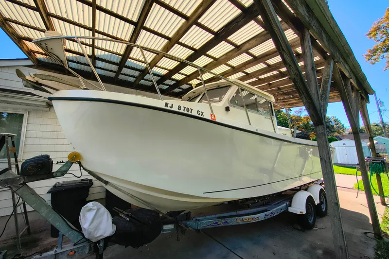 The Image of 2004 Osprey 26 Fisherman boat on trailer under a wooden canopy. - 0