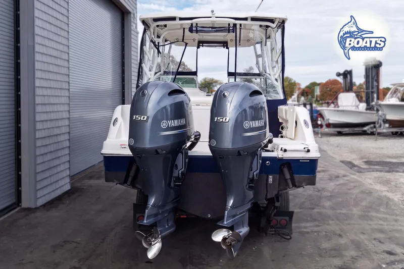 Slide: The Image of 2019 Robalo R247 Dual Console boat with twin Yamaha 150 engines, docked outdoors. - 12