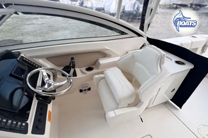 Slide: The Image of 2019 Robalo R247 Dual Console boat interior with steering wheel and white seating. - 4