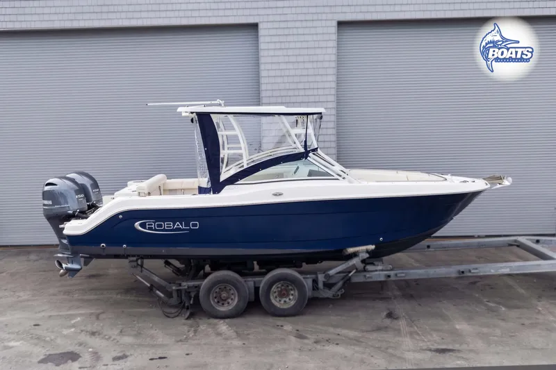 Slide: The Image of 2019 Robalo R247 Dual Console boat on trailer, blue and white design. - 1