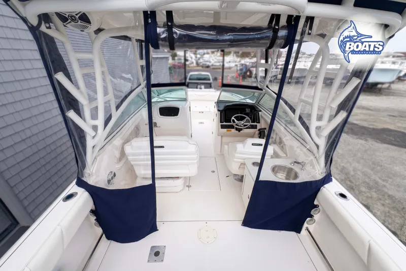 Slide: The Image of 2019 Robalo R247 Dual Console boat interior with seating, steering wheel, and blue canopy. - 8