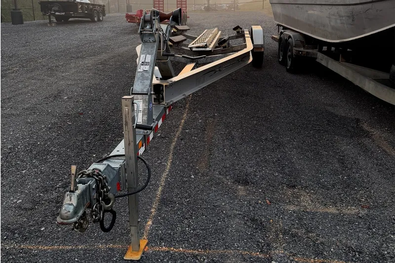 Slide: The Image of A boat trailer is parked on a gravel lot next to another trailer. - 15