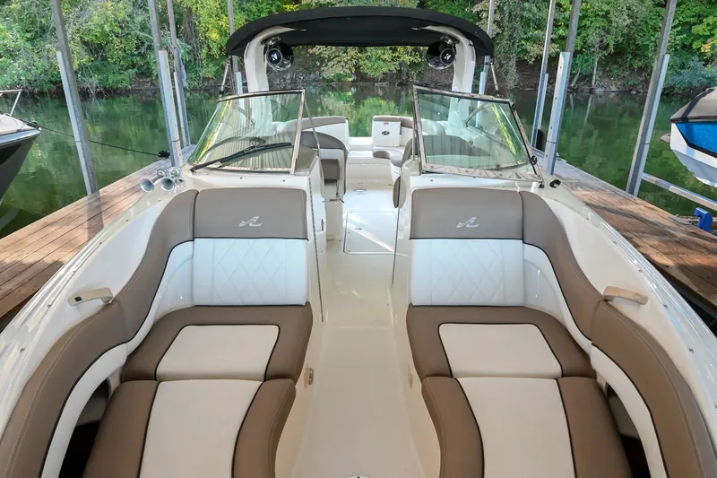 Slide: The Image of 2001 Sea Ray 290 Select EX boat interior with beige and white seating, docked by lush greenery. - 9