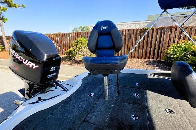 Slide: The Image of 2009 Ranger 208 VX boat with Mercury engine and blue seat, parked outdoors. - 7