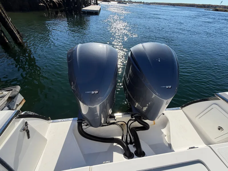 Slide: The Image of Two outboard engines on a boat in calm water, with a dock in the background. - 15