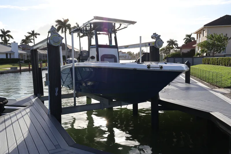 Slide: The Image of 2023 NauticStar 251 Hybrid boat docked on a lift in a sunny waterfront setting. - 49