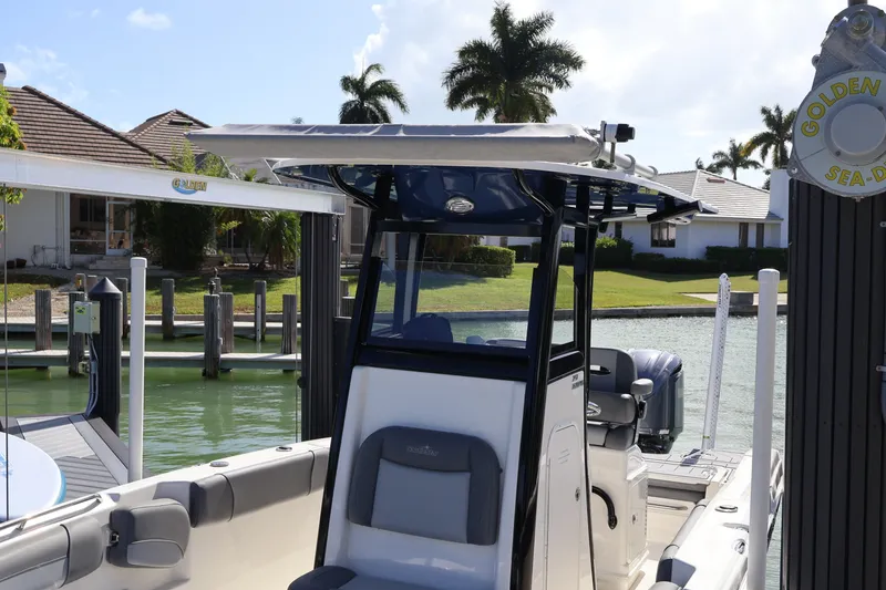Slide: The Image of 2023 NauticStar 251 Hybrid boat docked near waterfront homes and palm trees. - 38