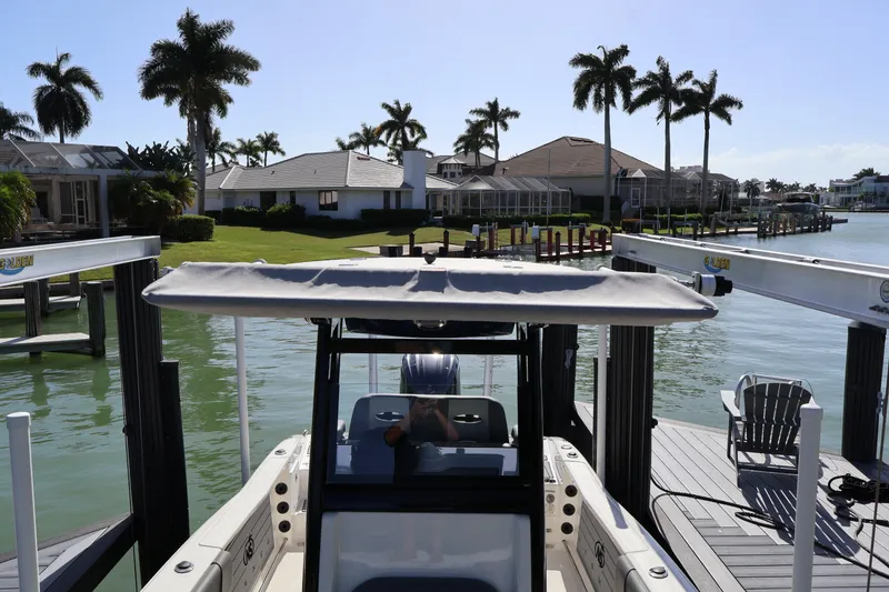 Slide: The Image of 2023 NauticStar 251 Hybrid boat docked near waterfront homes and palm trees. - 47