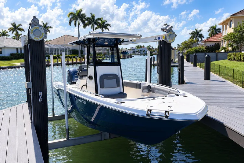 The Image of 2023 NauticStar 251 Hybrid boat docked on a sunny waterfront with palm trees. - 1