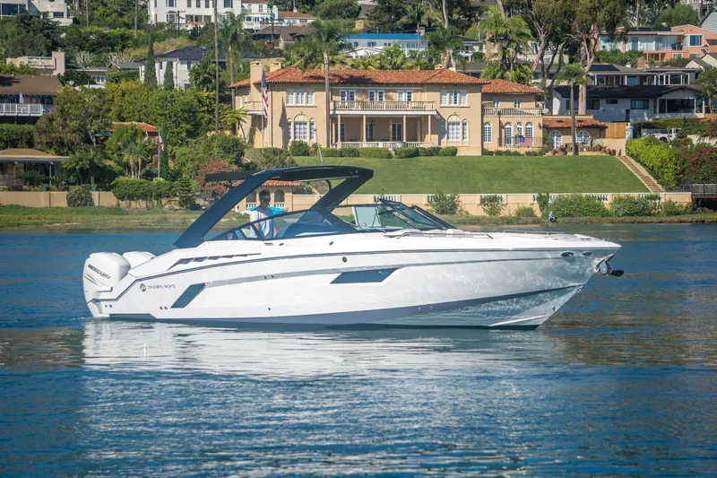 Slide: The Image of 2020 Cruisers Sport Series 338 Bow Rider on a serene lake with luxury homes in the background. - 4