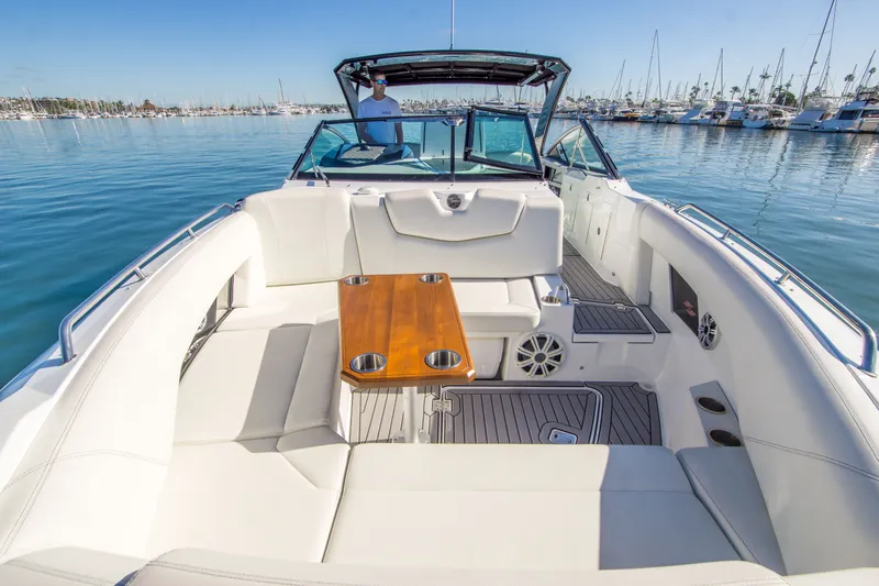 Slide: The Image of 2020 Cruisers Sport Series 338 Bow Rider with spacious seating and wooden table on calm water. - 31