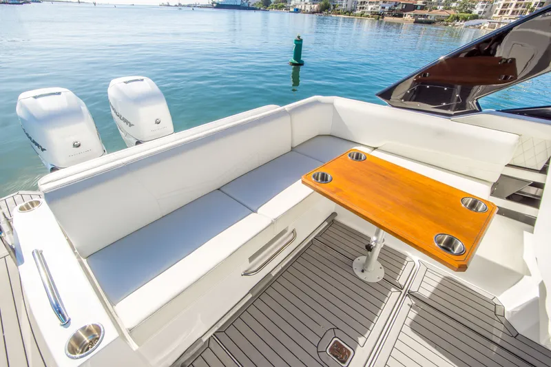 Slide: The Image of 2020 Cruisers Sport Series 338 Bow Rider with seating and table on deck, near water. - 10