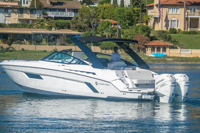 Slide: The Image of 2020 Cruisers Sport Series 338 Bow Rider boat on calm water near luxury homes. - 1