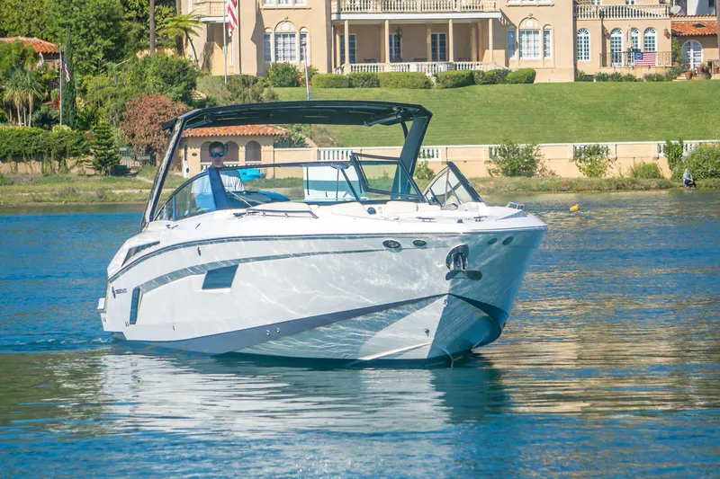 Slide: The Image of 2020 Cruisers Sport Series 338 Bow Rider on a serene lake near luxury homes. - 3