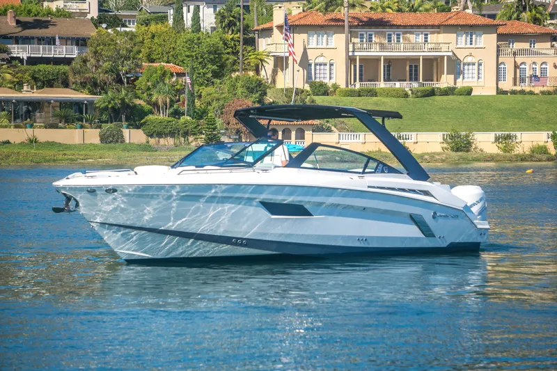 Slide: The Image of 2020 Cruisers Sport Series 338 Bow Rider on serene water near luxury homes. - 2