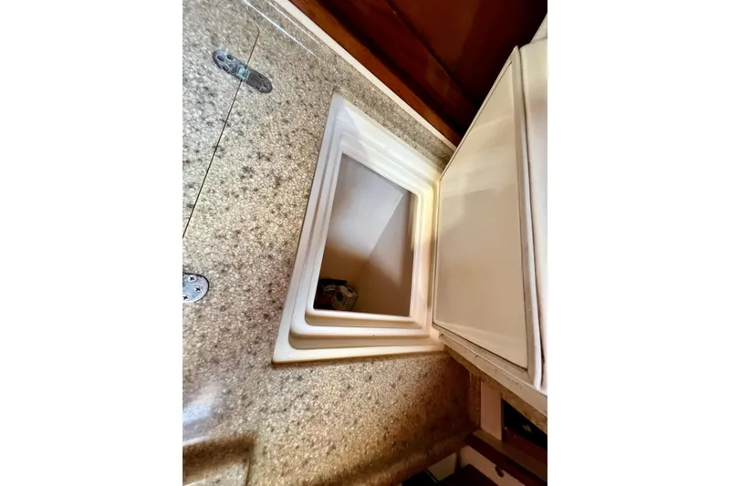 Slide: The Image of Open storage compartment on a 1975 Cape George 36 sailboat with granite-like countertop. - 72