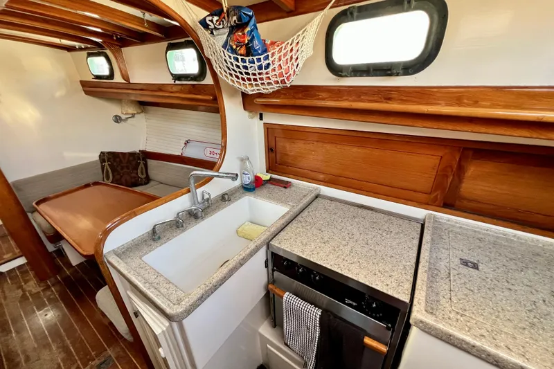 Slide: The Image of 1975 Cape George 36 yacht interior with wooden cabinetry and compact kitchen area. - 68
