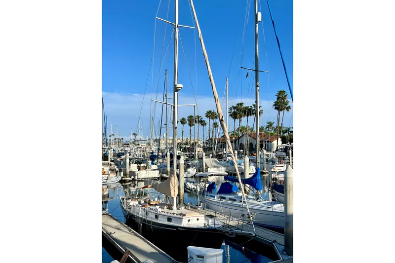 Slide: The Image of Sailboats docked at marina, featuring a 1975 Cape George 36 under clear blue skies. - 4