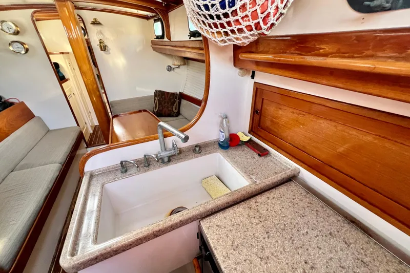 Slide: The Image of Interior of a 1975 Cape George 36 sailboat with wooden cabinetry and a compact kitchen sink. - 69