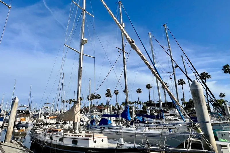 Slide: The Image of Sailboats docked at a marina under a clear blue sky, featuring a 1975 Cape George 36. - 1