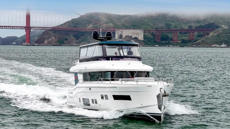 Slide: The Image of A 2020 Sirena 64 yacht cruising on the water with a bridge in the background. - 4