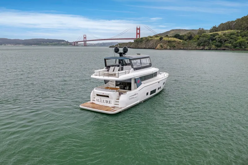 Slide: The Image of A luxurious 2020 Sirena 64 yacht cruising in a calm bay with a bridge in the background. - 14