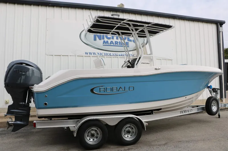 Slide: The Image of A 2027 Robalo R200 Center Console boat on a trailer in front of a building. - 12