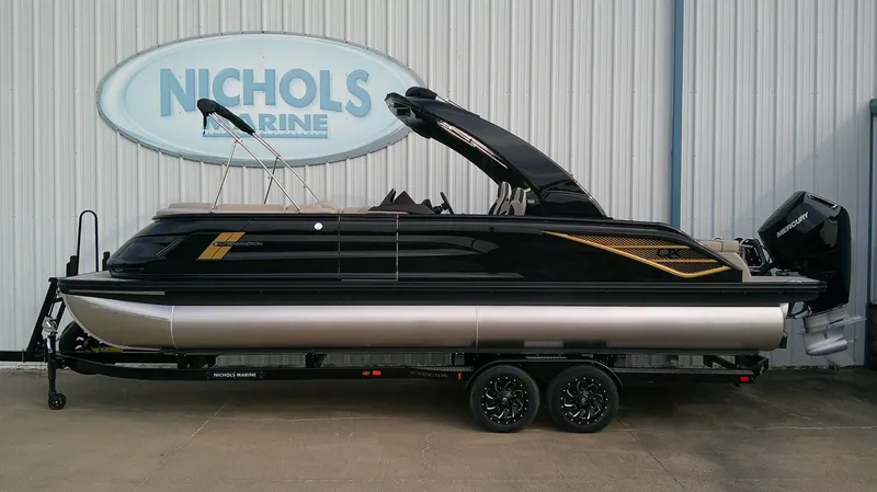 The Image of A sleek 2027 Bennington 25 QXSBA pontoon boat on a trailer in front of a building. - 0