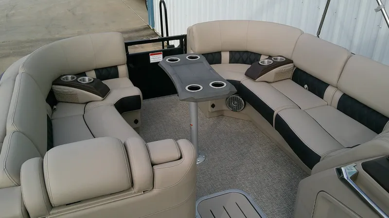 Slide: The Image of Interior of a 2027 Bennington 25 QXSBA with beige seating and a table with cup holders. - 6
