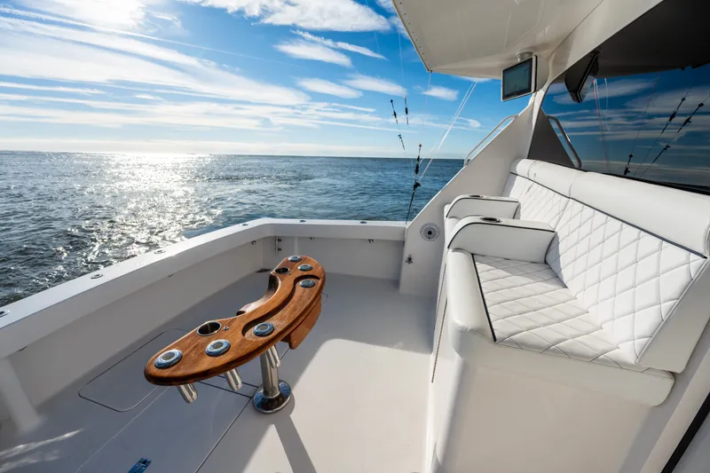 Slide: The Image of 2005 Viking 45 Convertible yacht deck with ocean view, featuring white seating and fishing rod holders. - 20