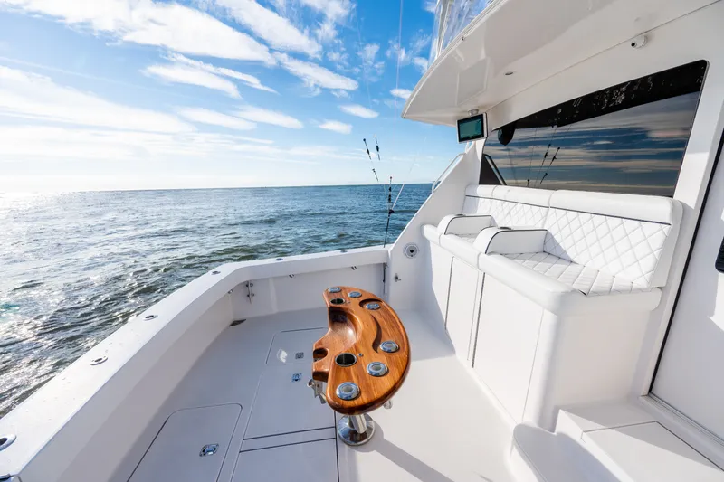 Slide: The Image of 2005 Viking 45 Convertible yacht deck with ocean view, featuring white seating and wooden table. - 21