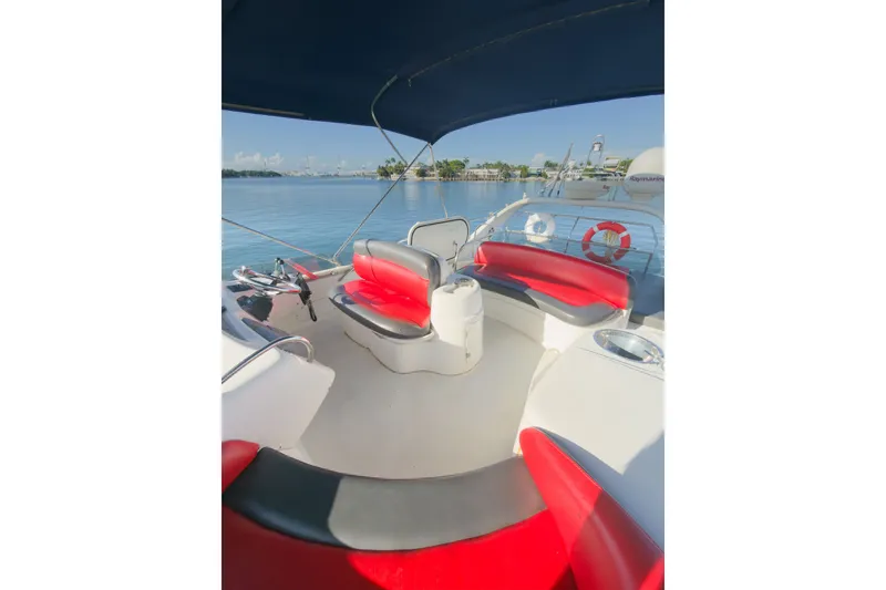 Slide: The Image of 2002 Cranchi Atlantique 50 yacht interior with red and gray seating, overlooking calm waters. - 8