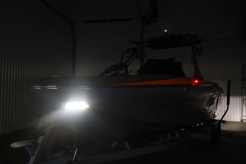 Slide: The Image of 2025 Axis T250 boat in dimly lit indoor setting with headlights on. - 58