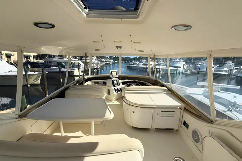 Slide: The Image of 2000 Sea Ray 560 Sedan Bridge interior with helm, seating, and marina view. - 8