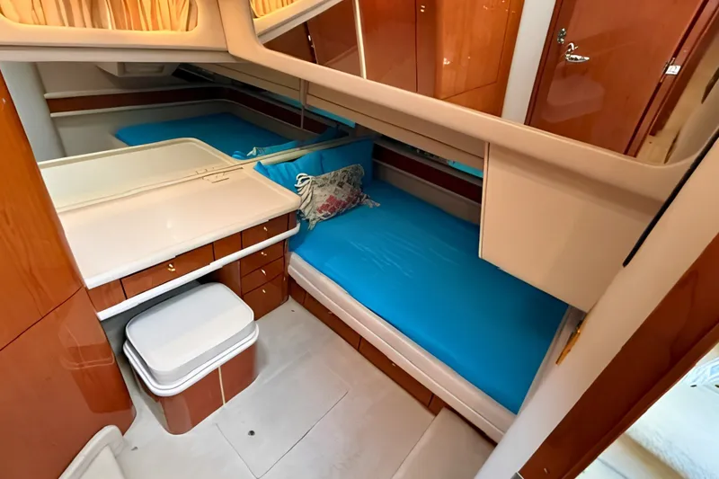 Slide: The Image of 2000 Sea Ray 560 Sedan Bridge cabin with blue bedding and wooden cabinetry. - 17