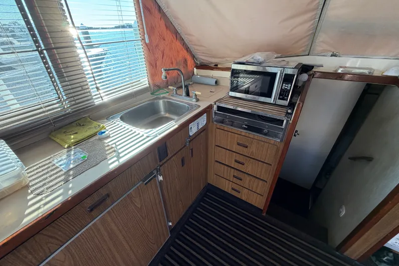 Slide: The Image of 1971 Bertram 35 Sport Fisherman interior kitchen with sink, microwave, and wooden cabinets. - 22