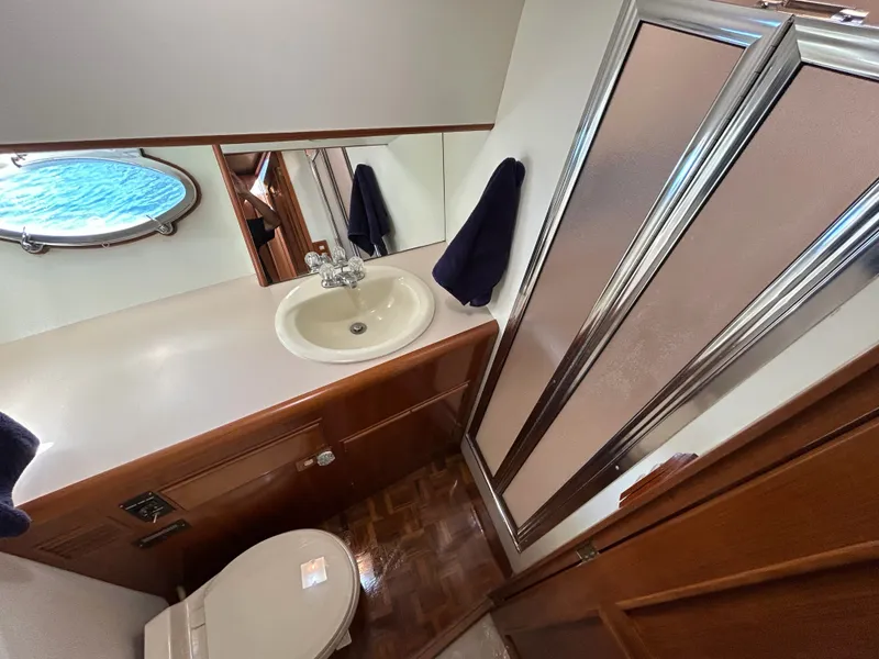 Slide: The Image of Bathroom with sink, toilet, and shower in a yacht. Wood paneling and porthole visible. - 20