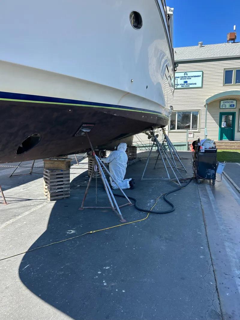 Slide: The Image of A worker in protective gear works on the hull of a motoryacht in a dry dock. - 30
