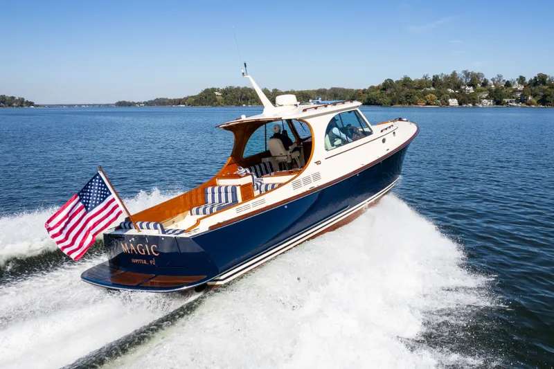 Slide: The Image of 2017 Hinckley Picnic Boat 37 MKIII cruising on a lake with American flag. - 2