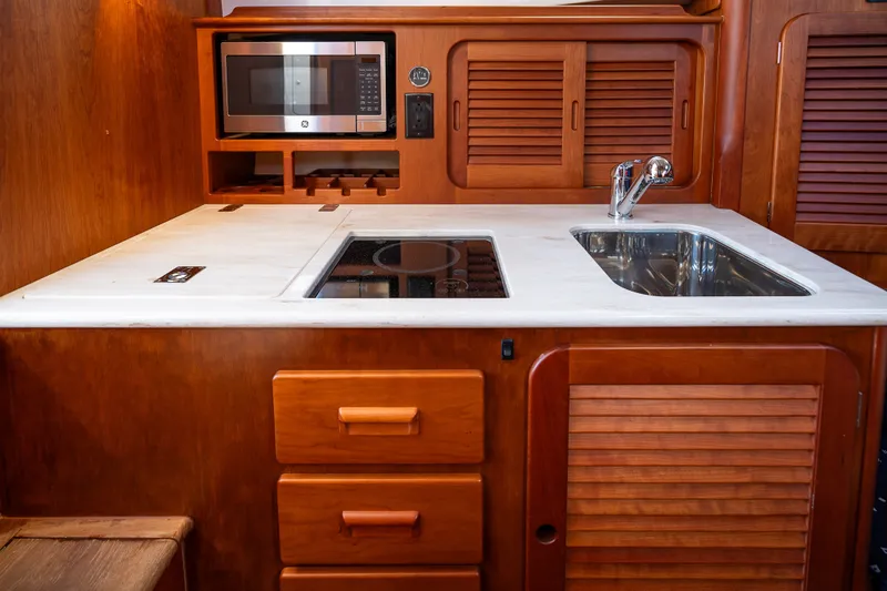 Slide: The Image of Hinckley Picnic Boat 37 MKIII 2017 galley with microwave, sink, and wooden cabinetry. - 34