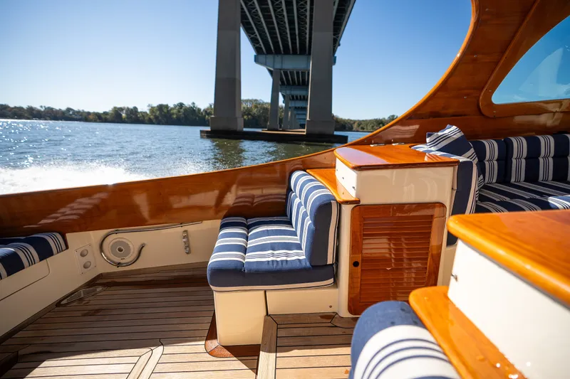Slide: The Image of 2017 Hinckley Picnic Boat 37 MKIII interior with striped seating under a bridge on a sunny day. - 14