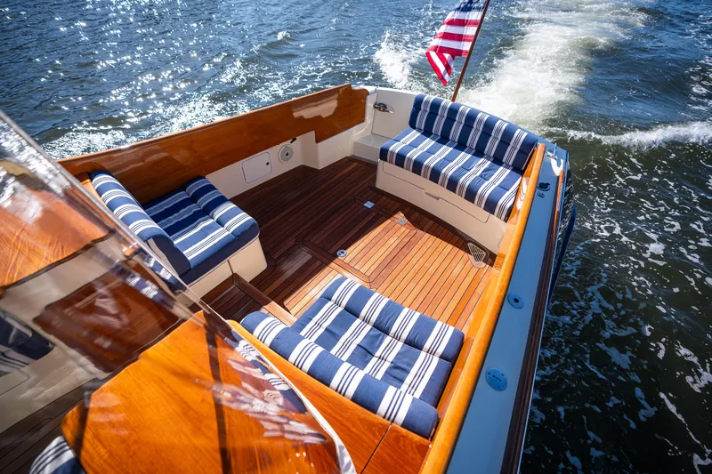 Slide: The Image of Hinckley Picnic Boat 37 MKIII, 2017, with striped seating and wooden deck on water. - 10