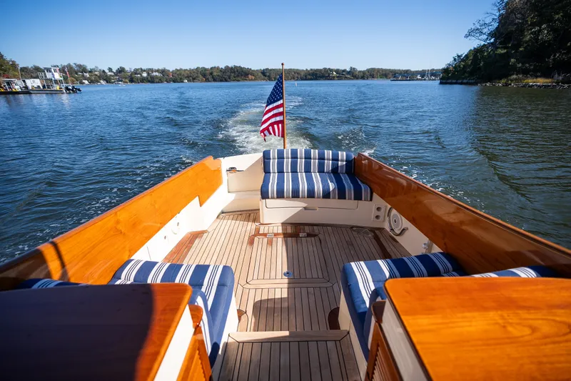 Slide: The Image of 2017 Hinckley Picnic Boat 37 MKIII cruising on a serene lake with striped seating. - 11