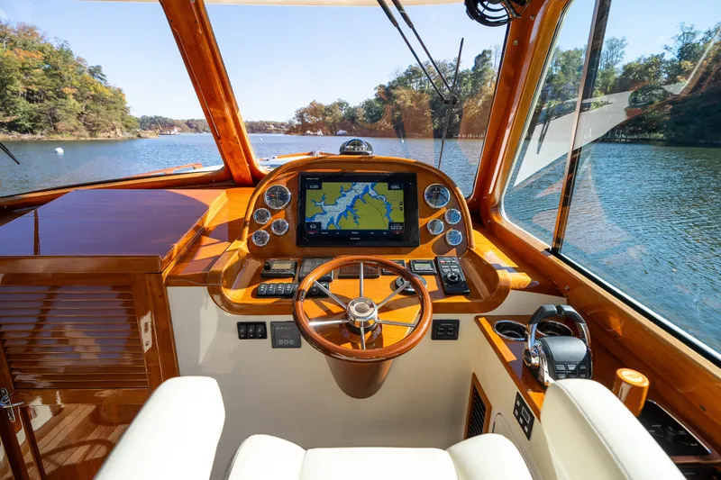 Slide: The Image of Helm of 2017 Hinckley Picnic Boat 37 MKIII with navigation display, steering wheel, and scenic water view. - 24