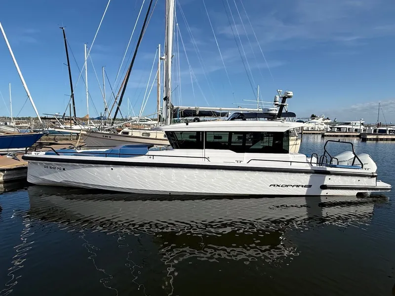The Image of The 2024 Axopar 37 XC Cross Cabin is docked in a marina, featuring a sleek design. - 0