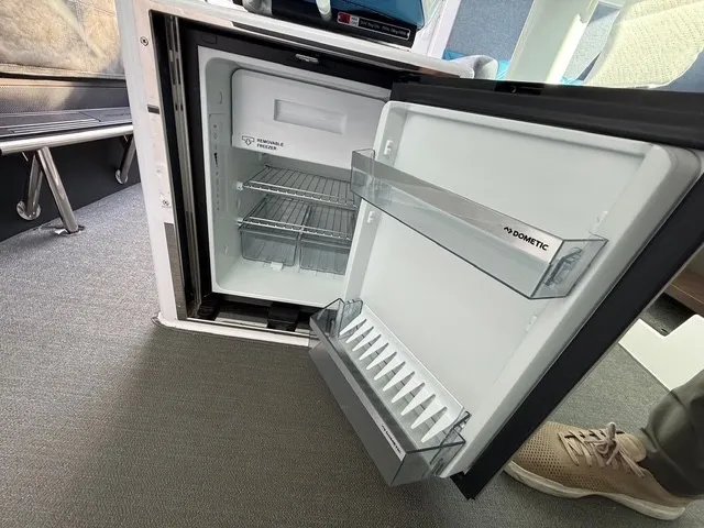 Slide: The Image of An open refrigerator in a boat cabin with gray carpet flooring. - 27