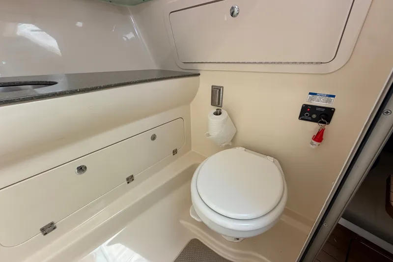 Slide: The Image of 2014 Boston Whaler 315 Conquest boat bathroom with toilet and storage compartments. - 52